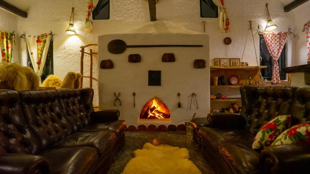 a living room with two leather couches and a fireplace at Mountain Views Chalet in Porumbacu de Sus
