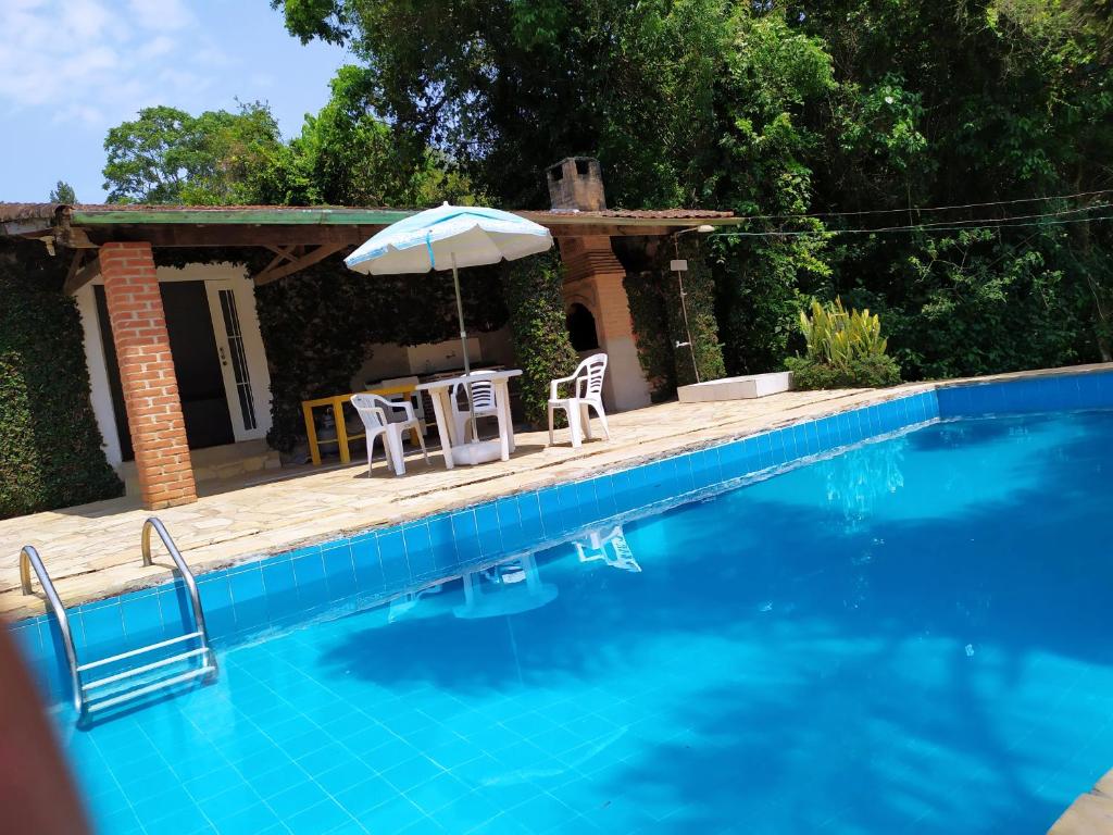 - une piscine avec 2 chaises et un parasol dans l'établissement Sítio Casarão, à Nazaré Paulista