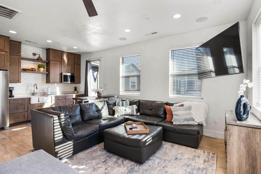 a living room with a black leather couch and a kitchen at Casa De Luz Casita condo in St. George