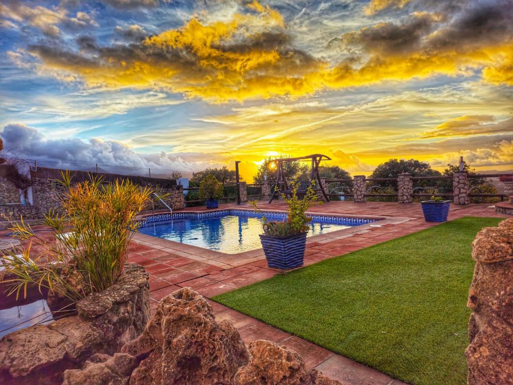 a pool in a yard with a sunset in the background at JARANDALUS (casa con atractivo y encanto) in El Gastor