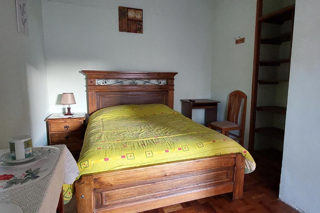 a bedroom with a wooden bed with a yellow bedspread at Cómoda habitación con baño privado in Sucre
