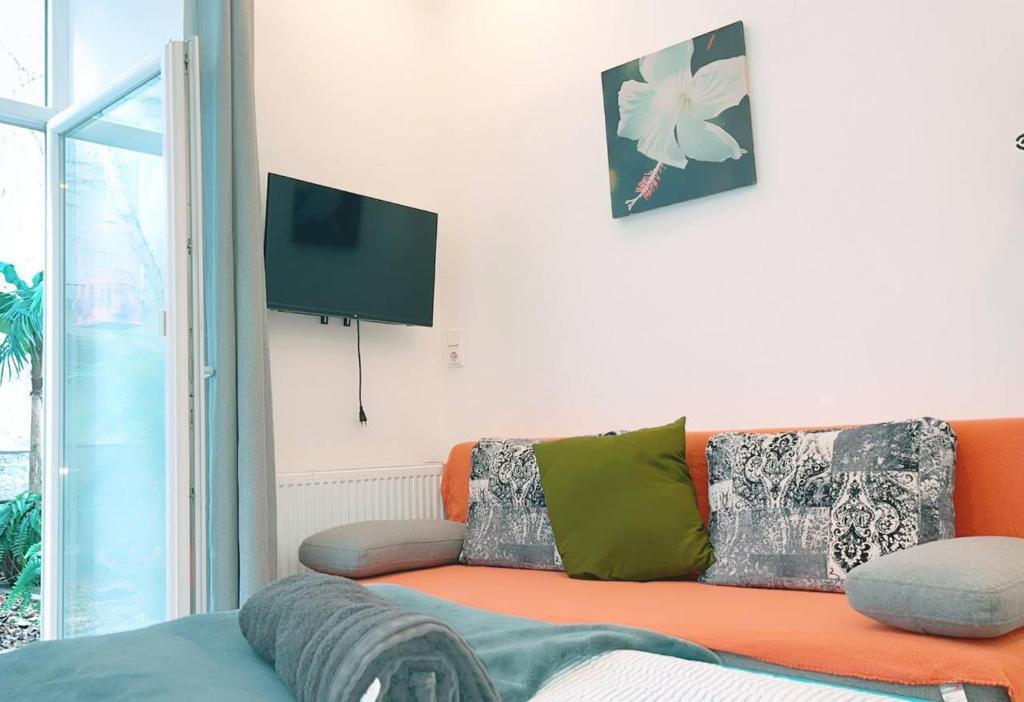 a living room with an orange couch and a tv at Comfort Triple room HN in Vienna