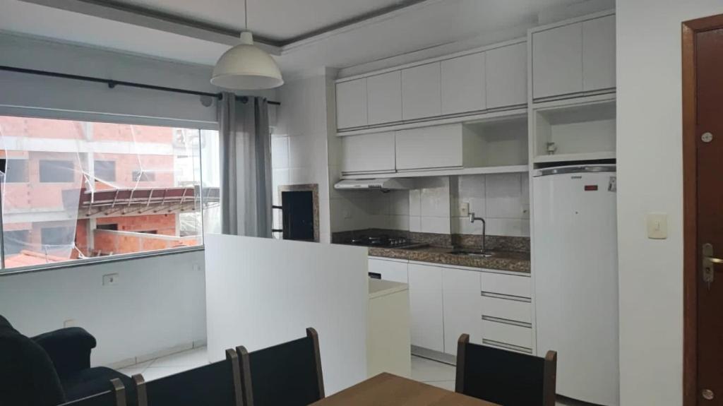 a kitchen with white cabinets and a large window at Ed Hang in Porto Belo