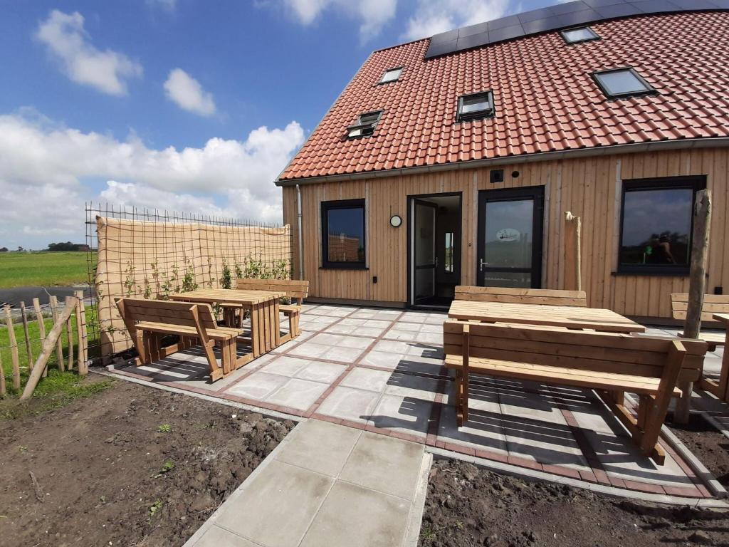 Leons的住宿－20-person group home in the heart of Friesland，大楼前方设有长椅和桌子的庭院