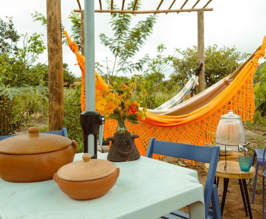 a dining table with a hammock in the background at Blue House Vale do Capão in Palmeiras