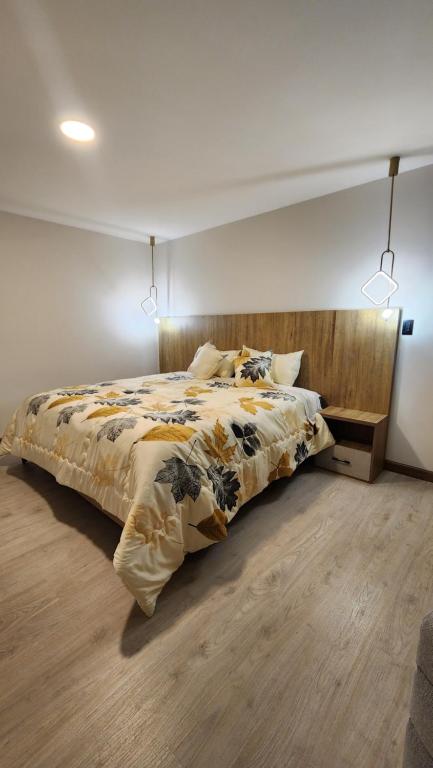 een slaapkamer met een groot bed met een houten hoofdeinde bij 203 La Terraza departamento in Cuenca