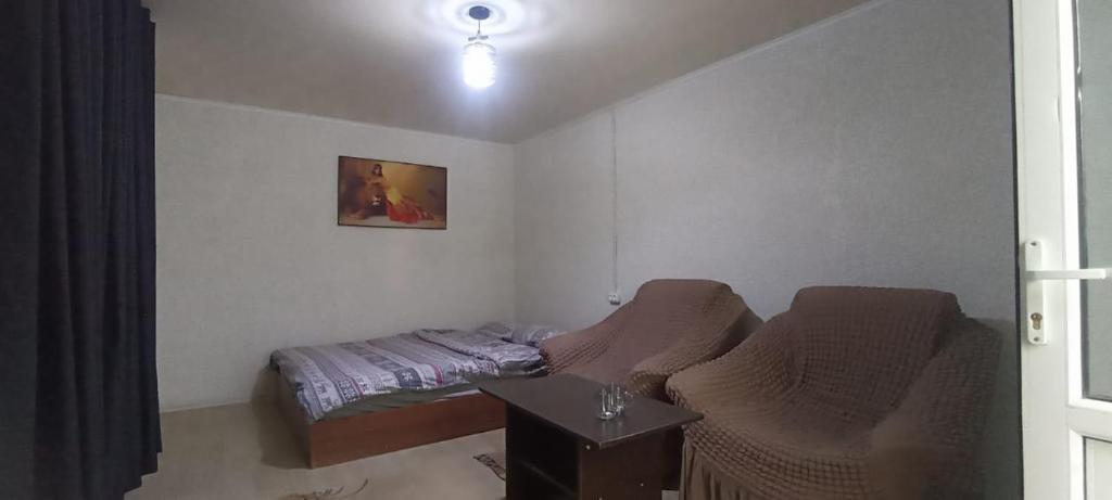 a small bedroom with a bed and a table at Космос in Bishkek