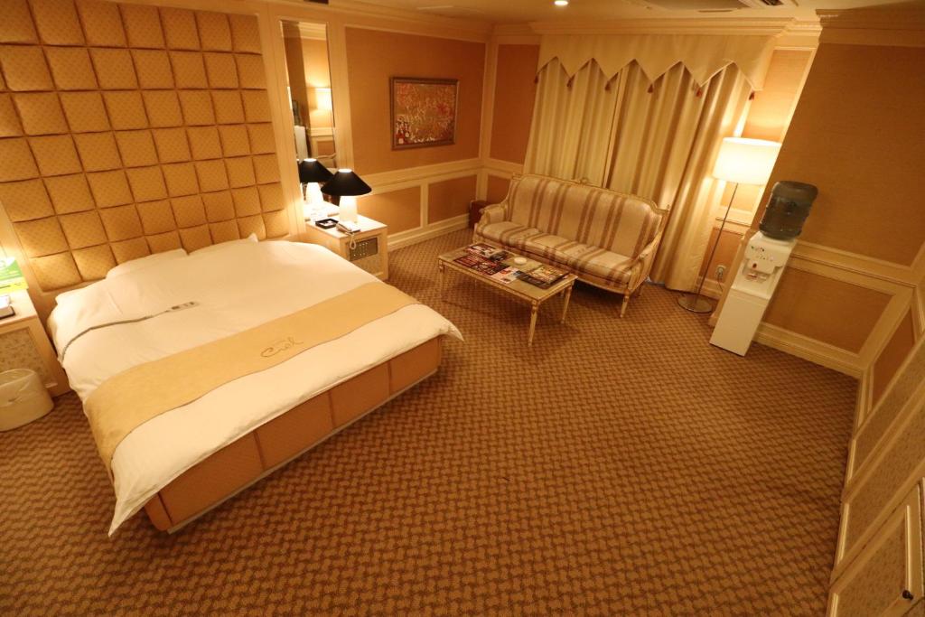 a hotel room with a bed and a chair at ホテルシエル in Himeji