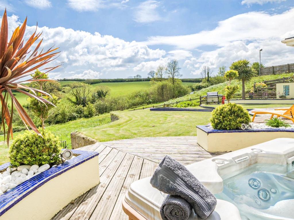 a hot tub on a deck with a garden at Pentire in Holbeton