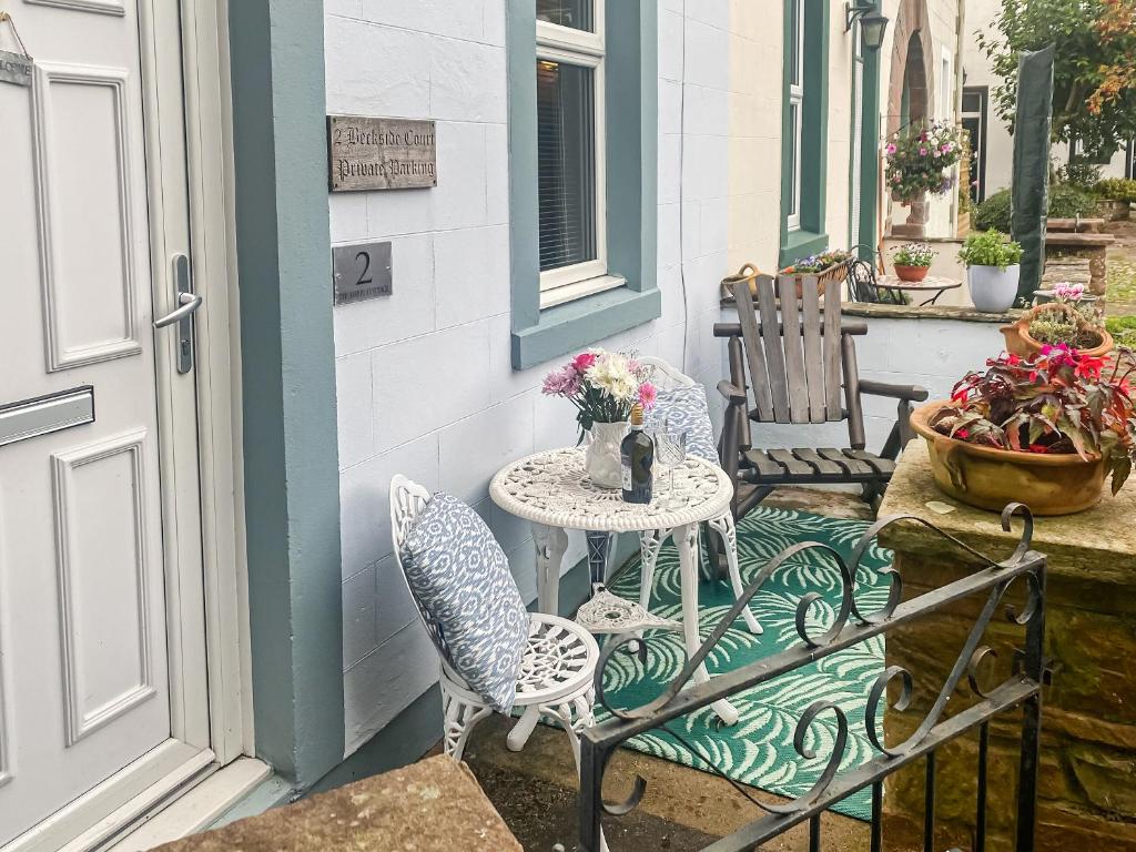 un patio con 2 sillas y una mesa con flores en Beckside Court en Brampton