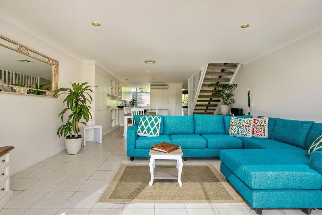a blue couch in a living room with a table at A Perfect Stay - 2 James Cook Apartments in Byron Bay