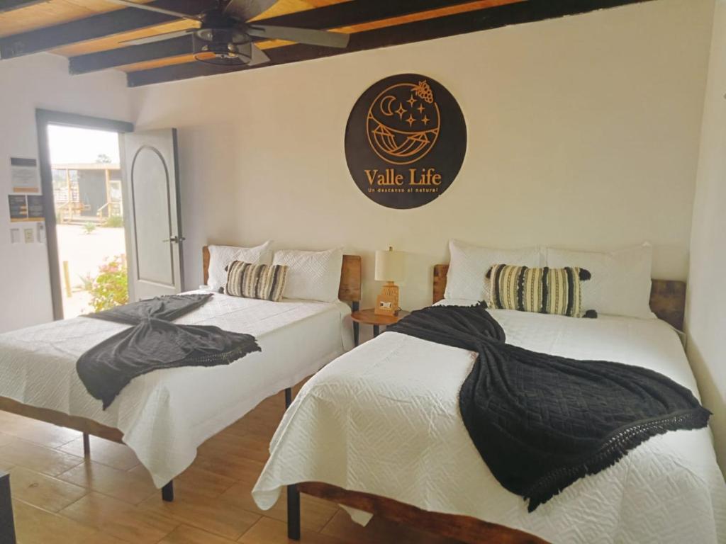 a bedroom with two beds and a clock on the wall at VALLE LIFE in Sansoni