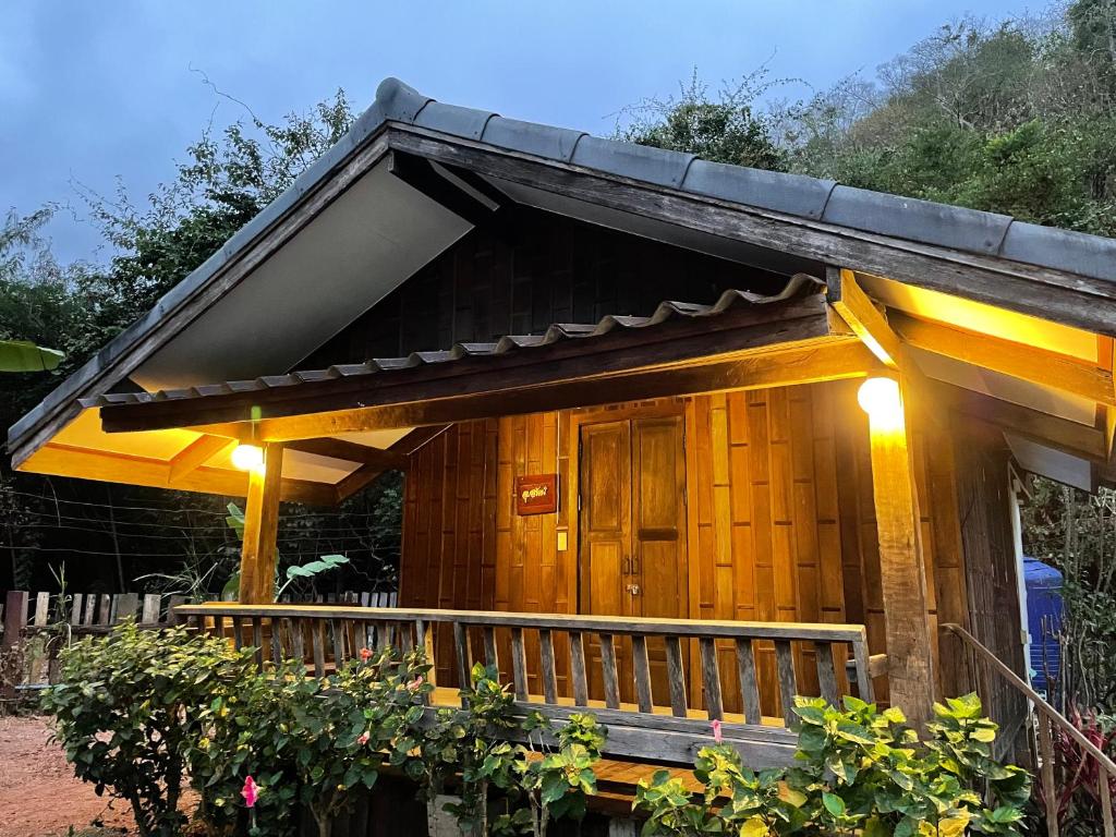 Una pequeña casa con un porche con luces. en บ้านระการีสอร์ต (Banraka Resort), en Ban Tha Chang