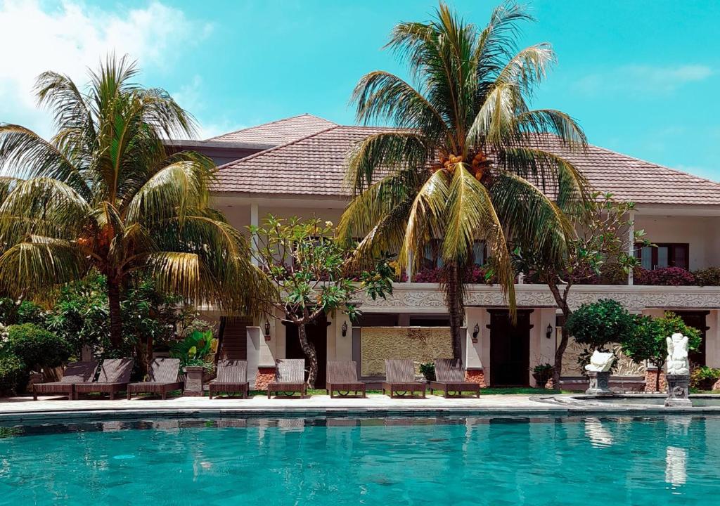 a house with palm trees and a swimming pool at Puri Saron Senggigi Hotel in Senggigi
