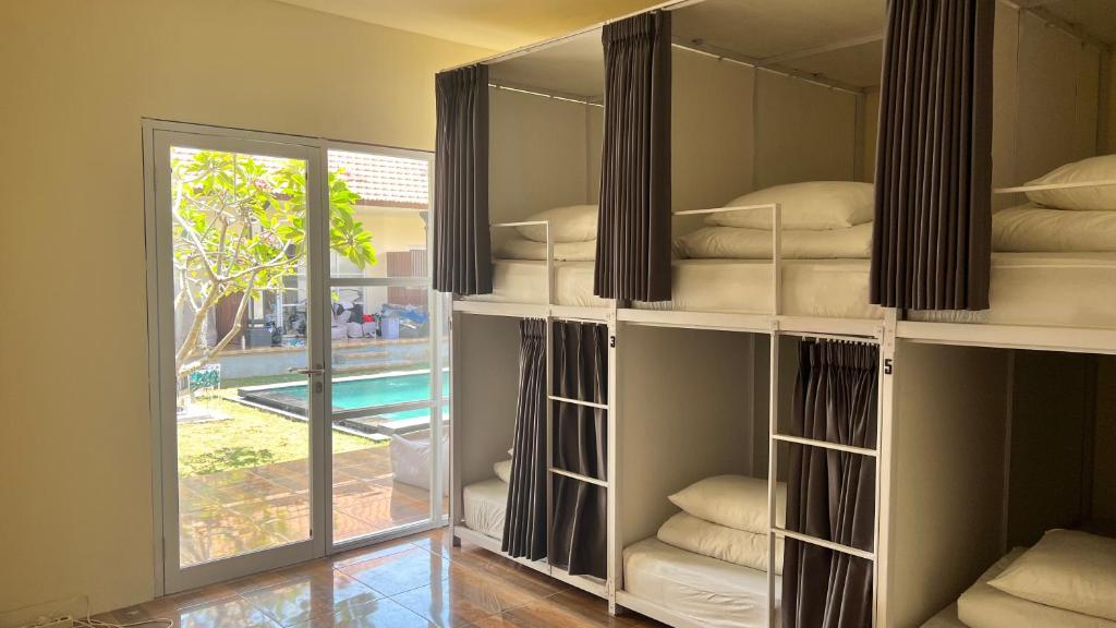 um quarto com prateleiras brancas com almofadas e uma janela em LoTide Surf Camp Uluwatu em Uluwatu
