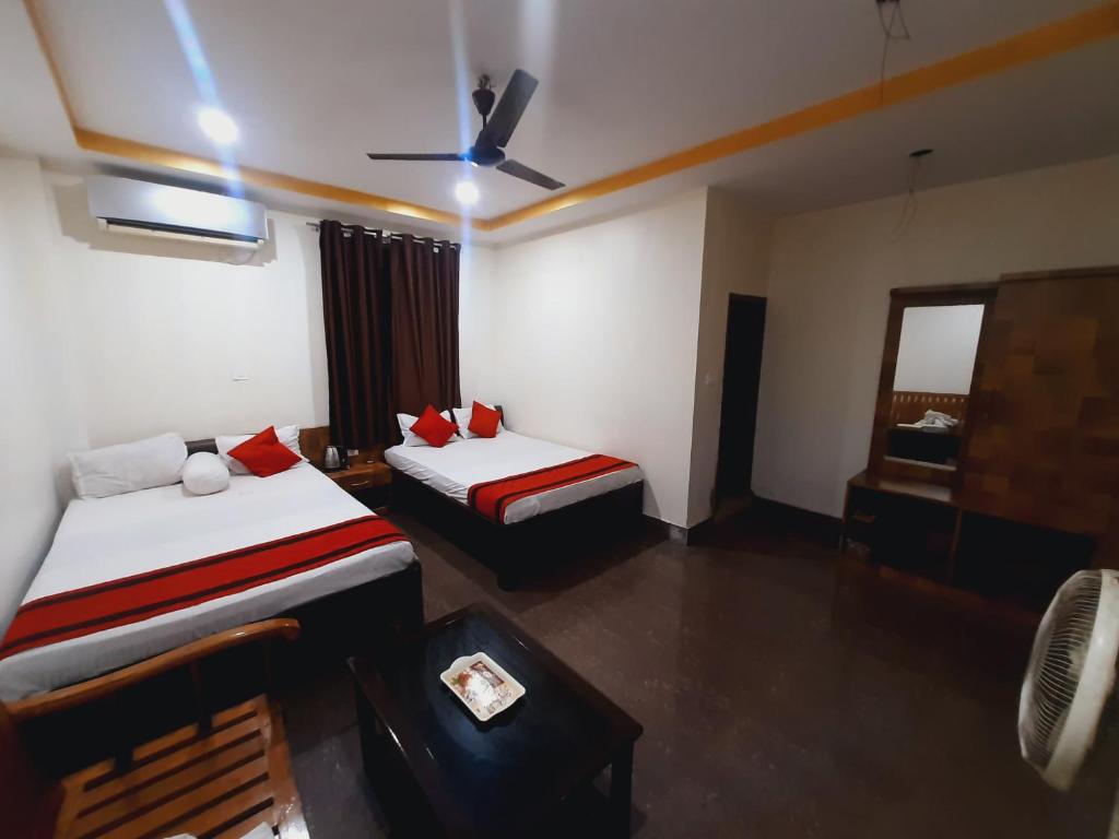 um quarto de hotel com 2 camas e uma ventoinha de tecto em Hotel Knight Inn Airport em Guwahati