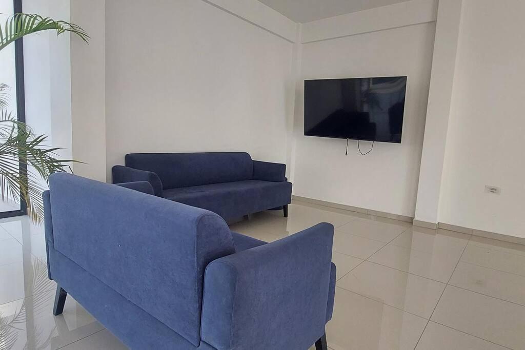 a living room with two blue chairs and a tv at Lujoso Dpto. en zona privilegiada. Amá Santa Cruz! in Santa Cruz de la Sierra