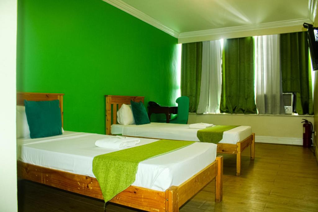 2 camas en una habitación con paredes verdes en Manila Airport Hotel by Urban Connect, en Manila