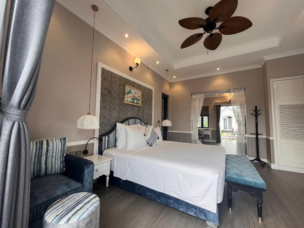 ein Schlafzimmer mit einem weißen Bett und einem Stuhl in der Unterkunft Sun Villa Thanh Liên Wyndham Vườn Vua Resort & Villas in Ðồng Phú