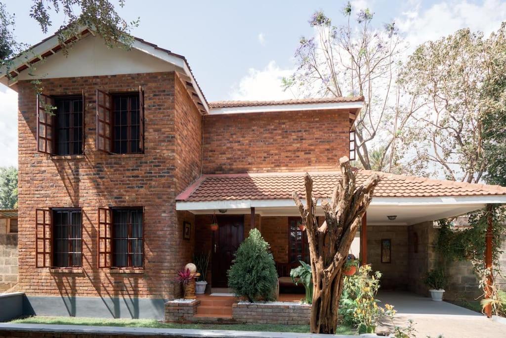 une maison en briques avec un arbre devant elle dans l'établissement Olive Home Arusha, à Nasulo