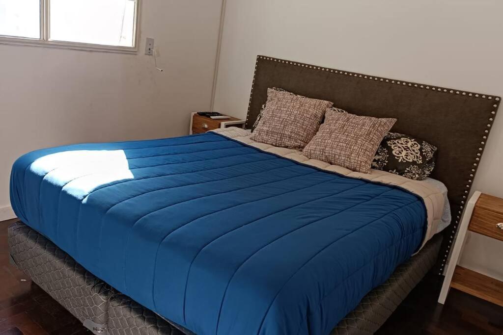 a bed with a blue blanket and pillows on it at Insuperable depto en san telmo. in Buenos Aires