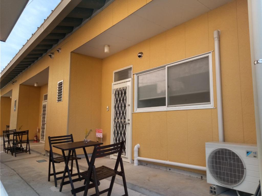 a patio with a table and chairs next to a building at Yellow House in Naoshima