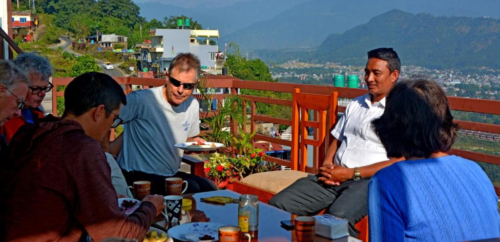 un grupo de personas sentadas alrededor de una mesa comiendo en Hotel Himalayan Home Pokhara Lamagaun 10 minute from Lakeside by car, en Pokhara