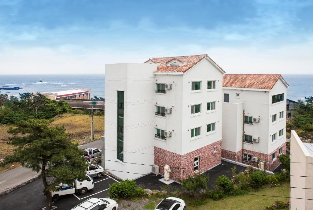 an apartment building with the ocean in the background at Jeju Aria Pension in Jeju