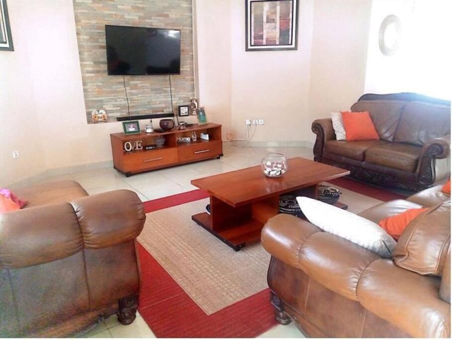 sala de estar con muebles de cuero y TV de pantalla plana en Heritage Accommodation, en Kigali