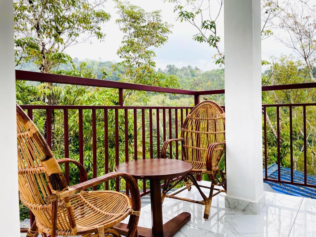 um pátio com 2 cadeiras e uma mesa na varanda em WinterHome homestay em Munnar