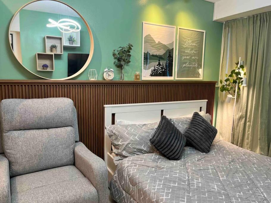 a bedroom with a bed and a chair and a mirror at Relaxing and Cozy Unit at The Residences in Manila