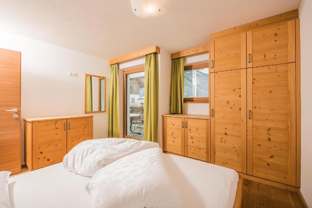 a bedroom with a white bed and wooden cabinets at Pichlerhof Apt 3 in Valle Di Casies
