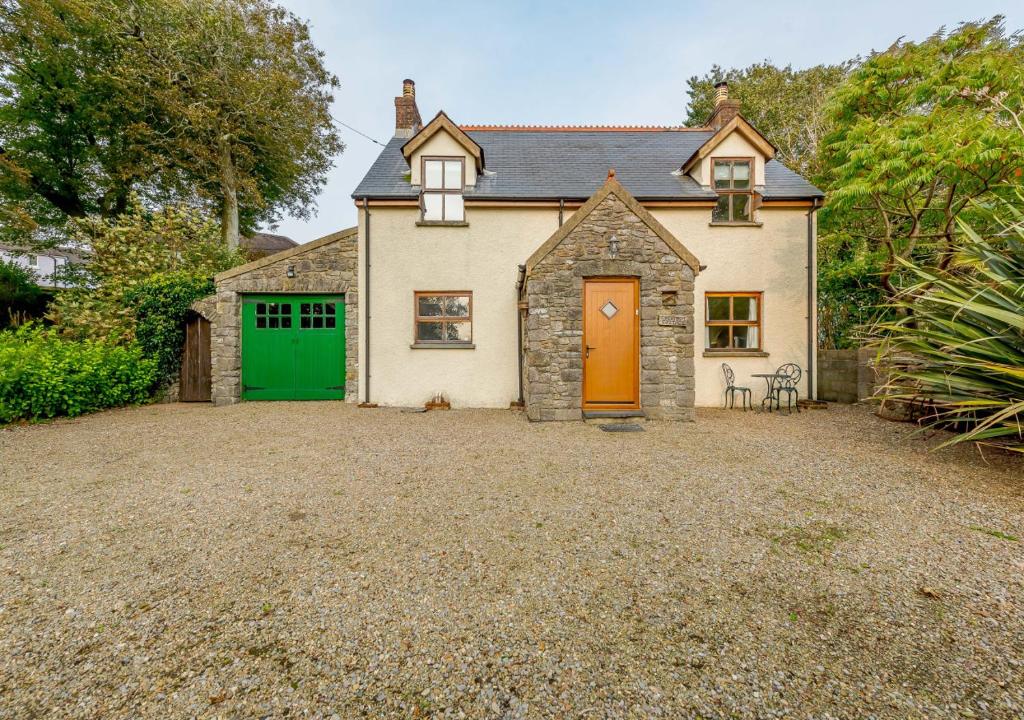 een huis met een groene deur en een grindoprit bij Chestnut Cottage in Manorbier