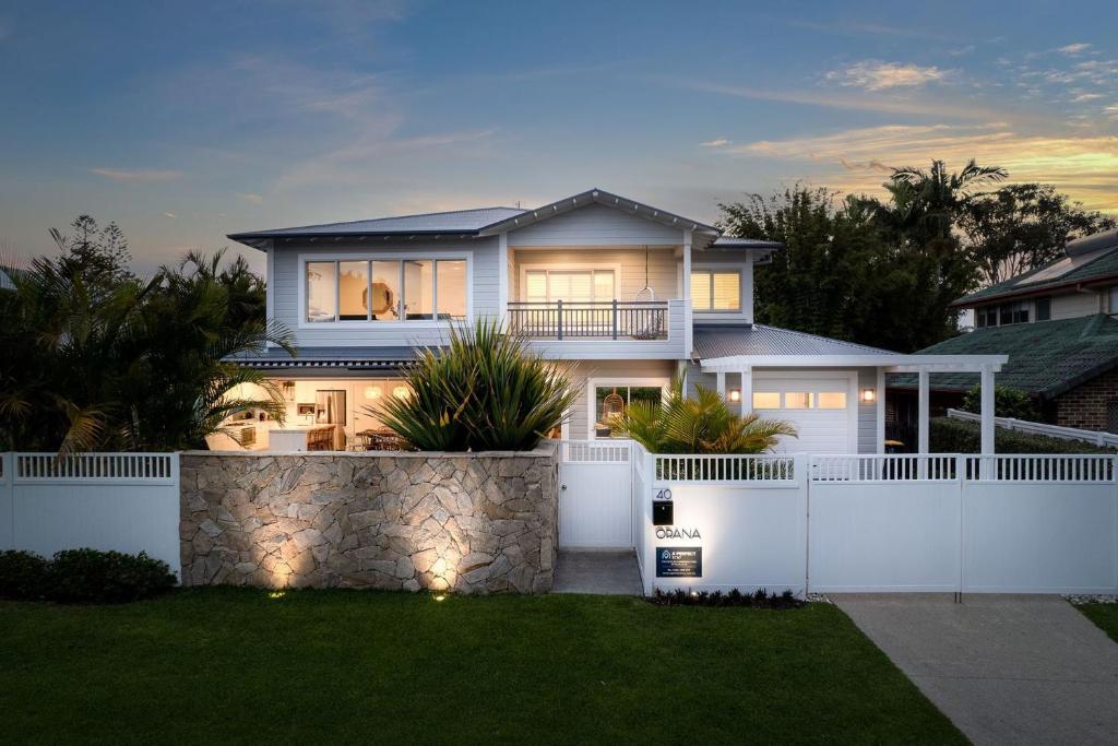a house with a white fence in front of a yard at Orana in Byron Bay