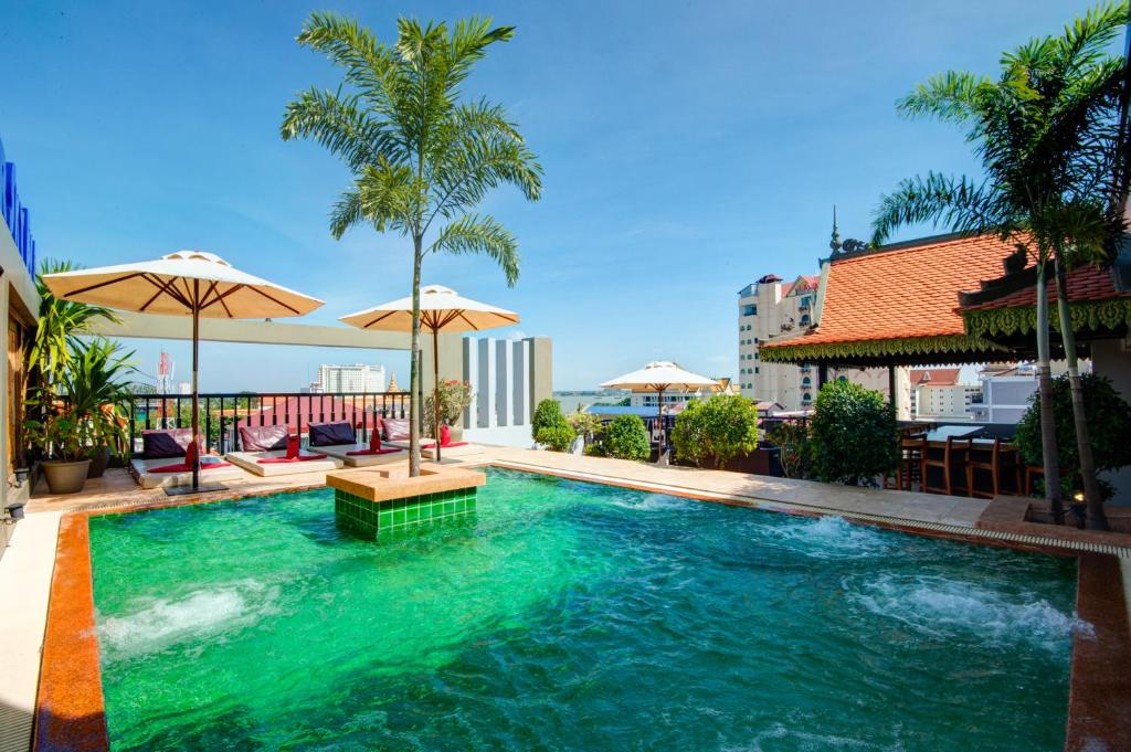 a swimming pool with green water and palm trees at Apsor Palace Hotel in Phnom Penh