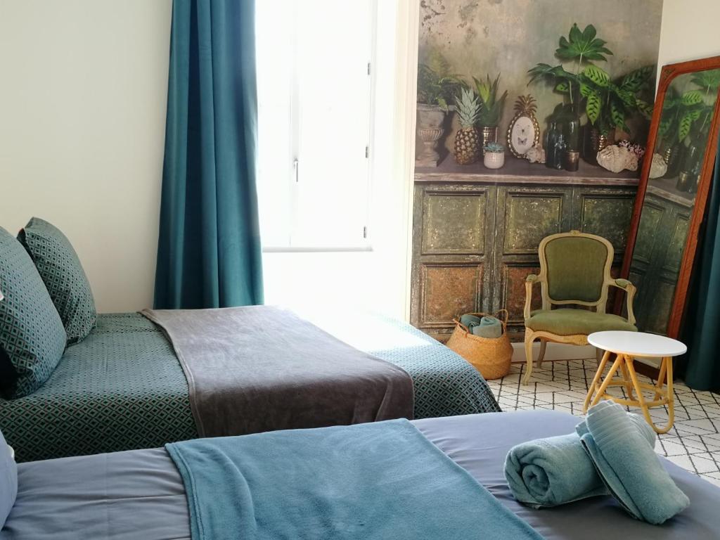 1 dormitorio con 2 camas, silla y ventana en le gîte du fou logement 8 pers 13mn puy du fou en Saint-Amand-sur-Sèvre