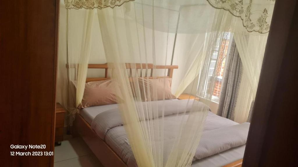 una camera con due letti con tende bianche e una finestra di Room in Guest room - Charming Room in Kayove, Rwanda - Your Perfect Getaway 