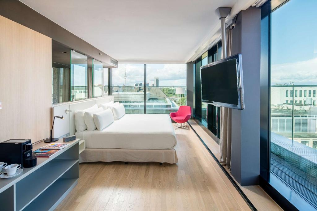 - une chambre avec un lit et une télévision à écran plat dans l'établissement Barceló Hamburg, à Hambourg