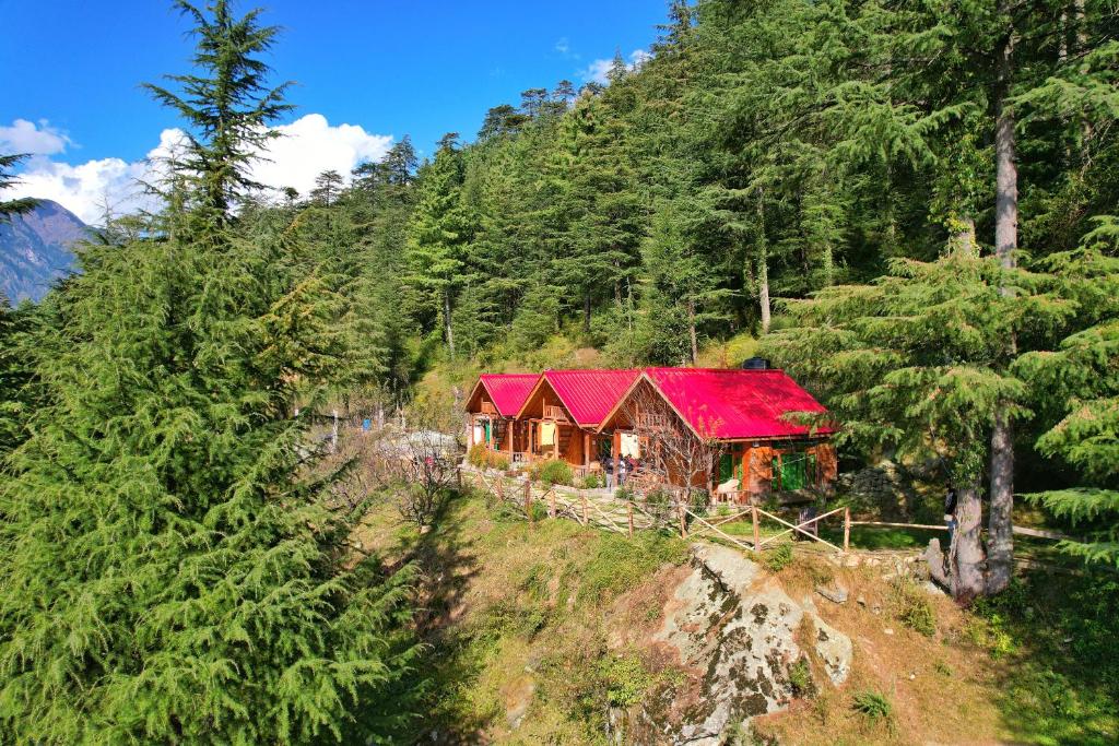 a house with a red roof in the middle of a forest at Himalayan Cedar Nest in Sainj