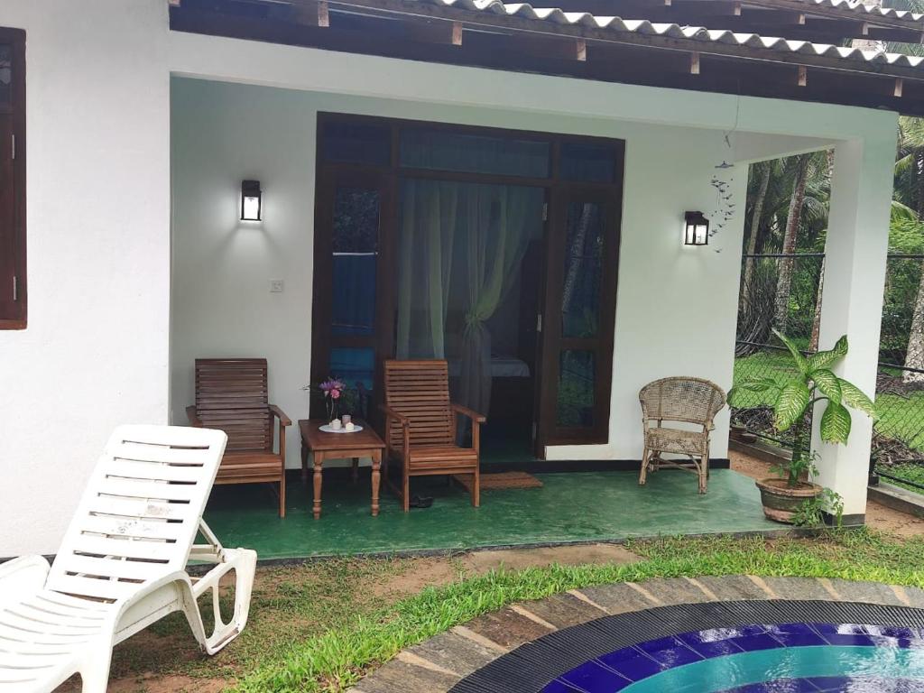a house with a patio with chairs and a pool at Palm Beach Cabana in Kosgoda