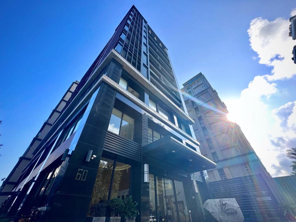 a tall glass building with the sun in the sky at Vasty Jiaoxi Hotel in Jiaoxi