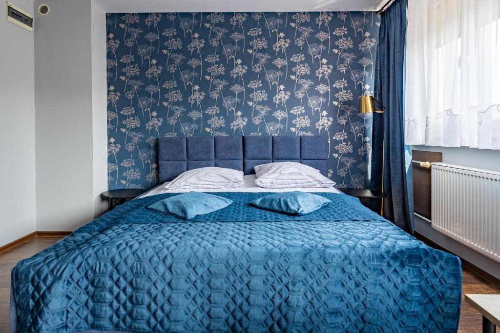 a bedroom with a blue bed with a blue blanket at Apartamenty Komfort in Częstochowa