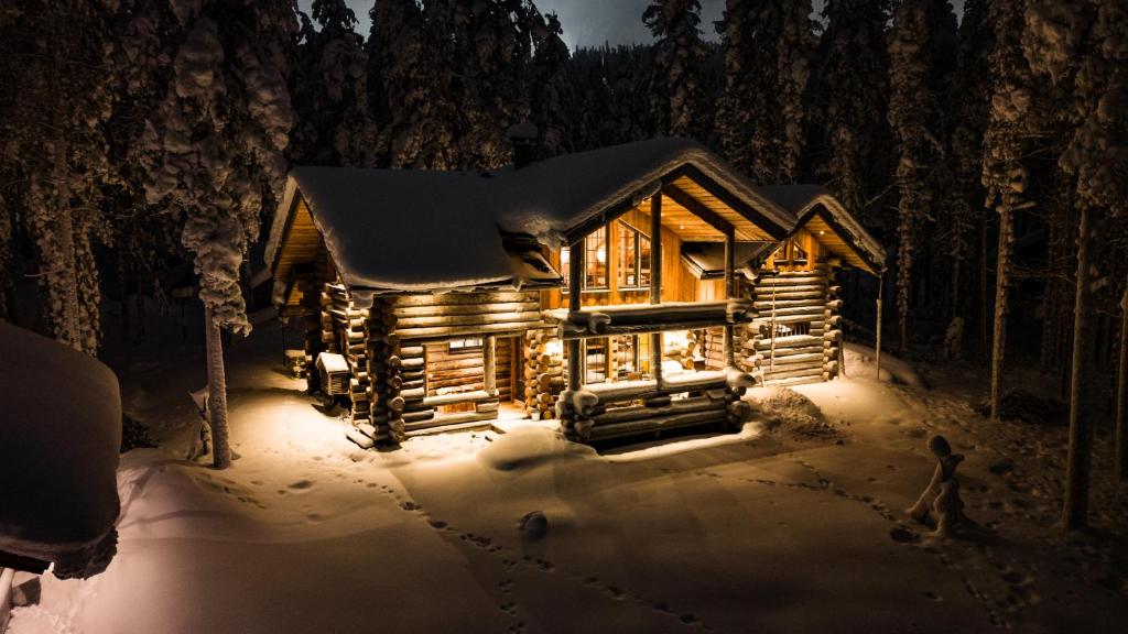 una cabaña de madera en la nieve por la noche en Kelomattila, en Levi