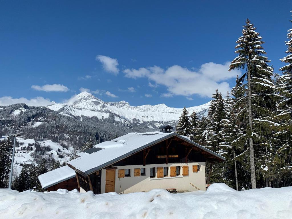 a house covered in snow with mountains in the background at Chalet Le Remarquable, Crest Voland in Crest-Voland