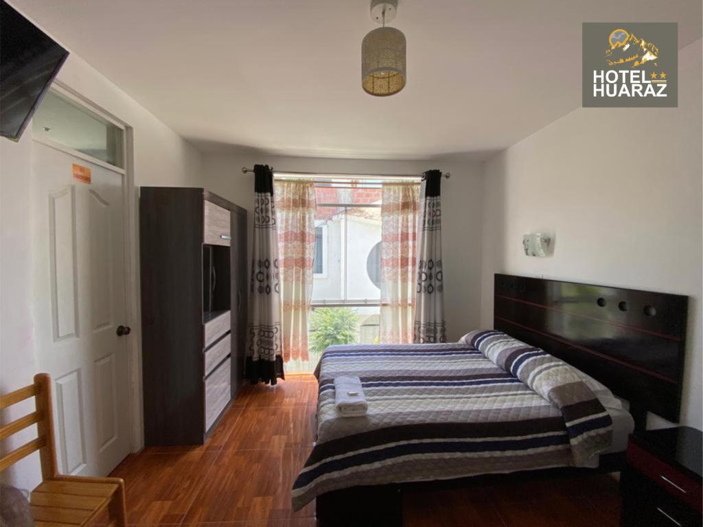 a bedroom with a bed and a large window at HOTEL HUARAZ in Tacna