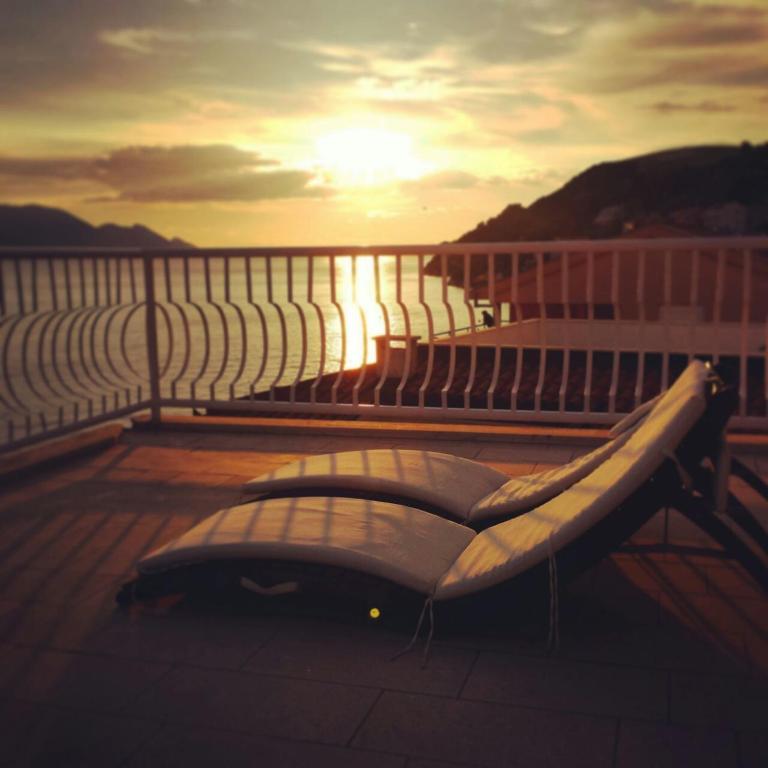 a bench on a balcony with the sunset in the background at Apartment Galeb Komarna in Komarna