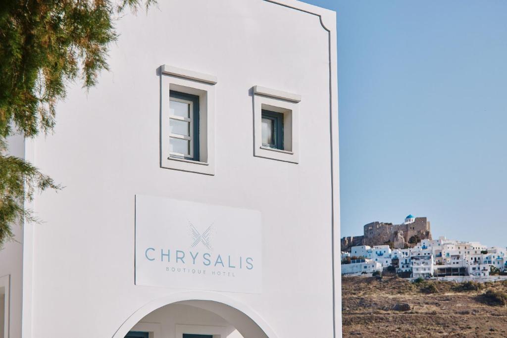a white building with a sign that reads chrysalis at Chrysalis Boutique - Adults Only in Astypalaia