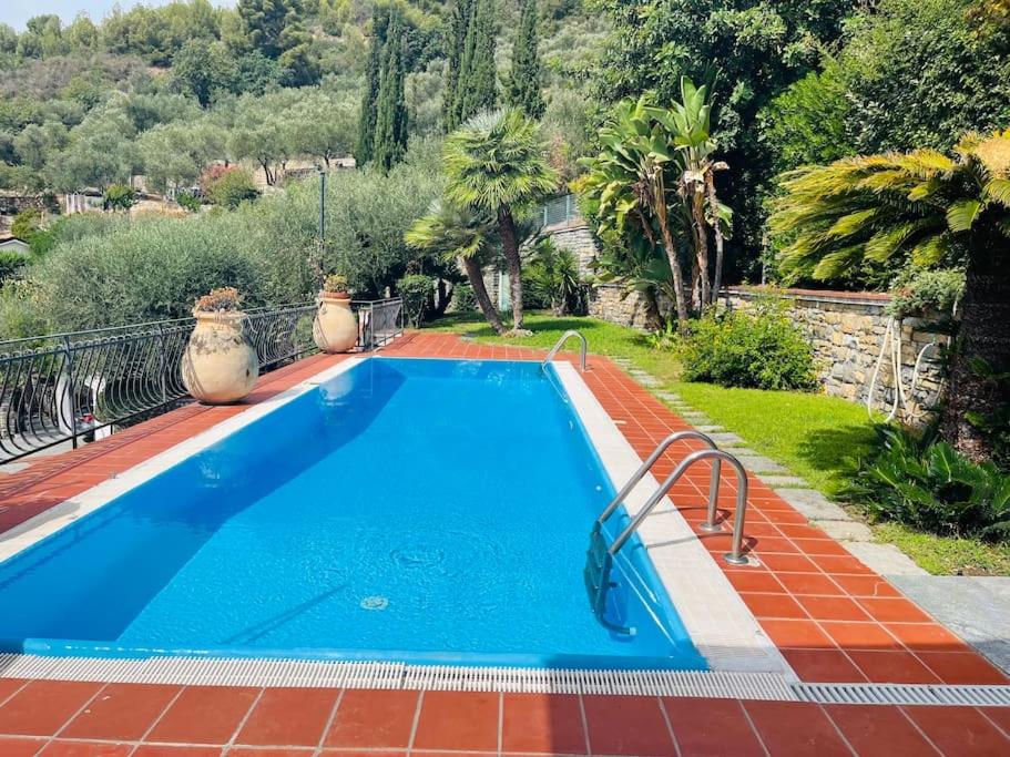 a large blue swimming pool in a yard with trees at Villa Le Anfore in Imperia
