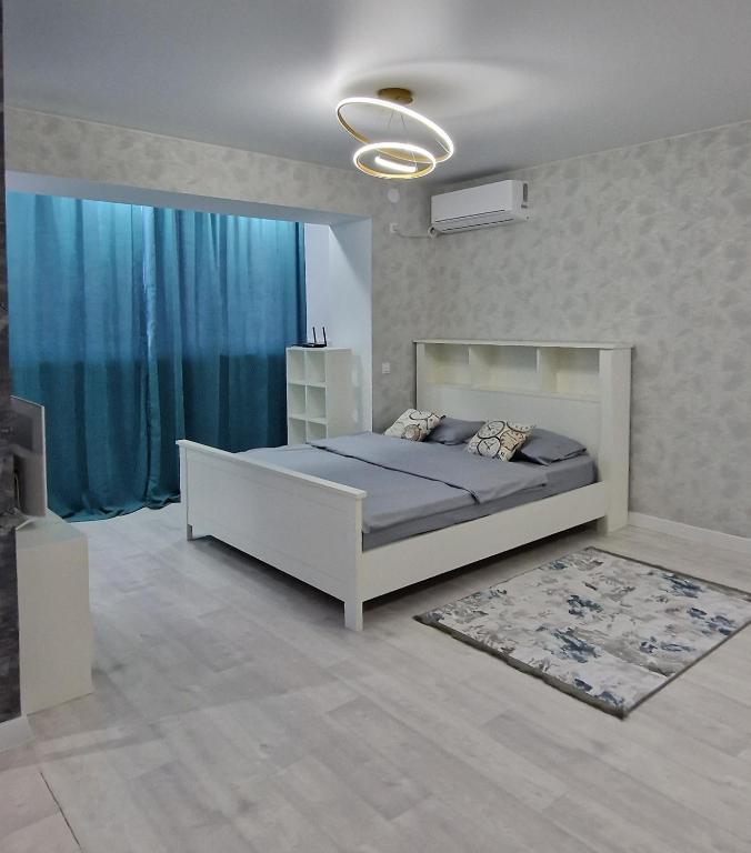 1 dormitorio con 1 cama grande y cortinas azules en Уютная студия, en Aktau