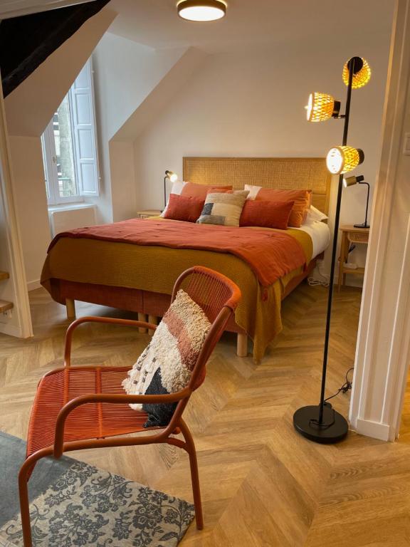 a bedroom with a bed and a chair and a lamp at Canopée - Appartement - Hyper centre ville in Quimper